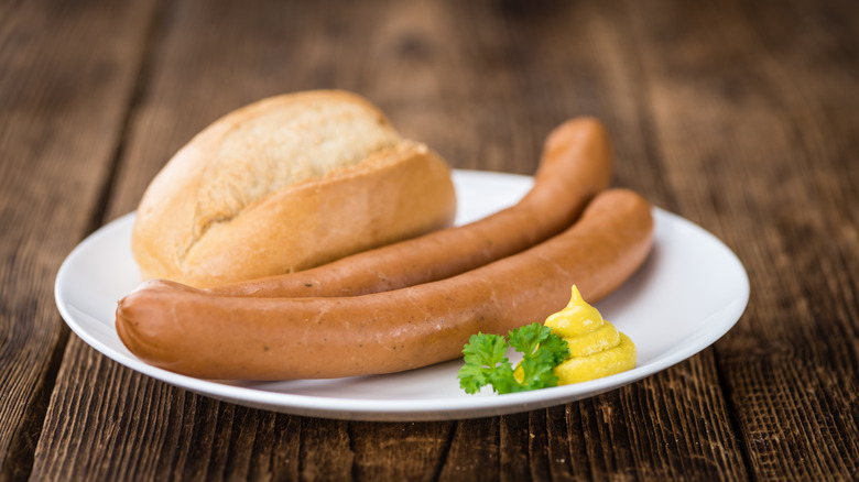 Bockwurst with roll and mustard on white plate