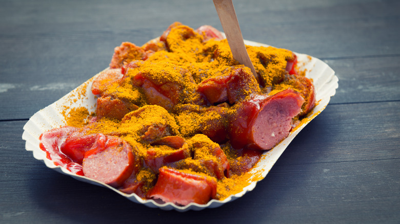 Paper plate of currywurst on a wooden table