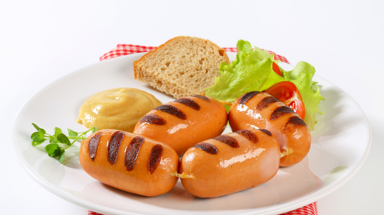 Grilled knackwurst on a white plate with mustard