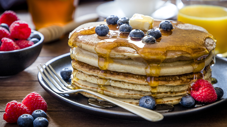 Stack of pancakes with butter, blueberries, and syrup