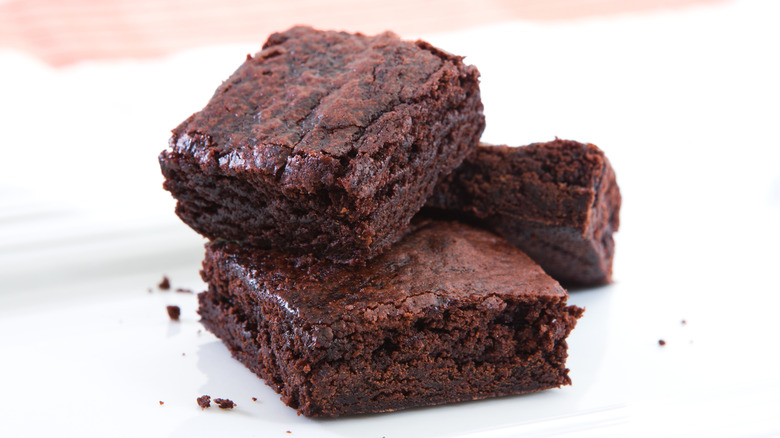 Three brownies stacked on a white surface