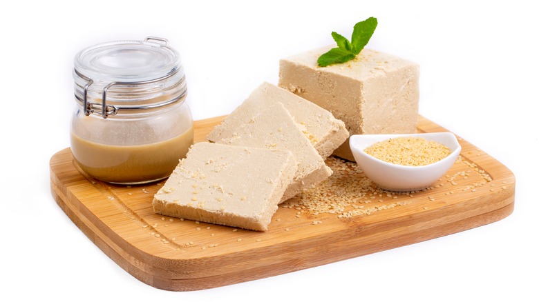 Halva slices on cutting board with tahini and sesame seeds