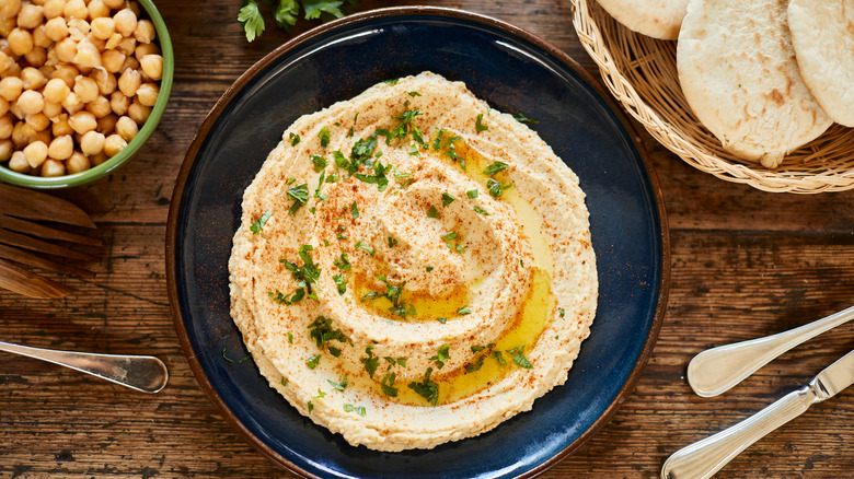 Blue bowl of hummus on a wooden table