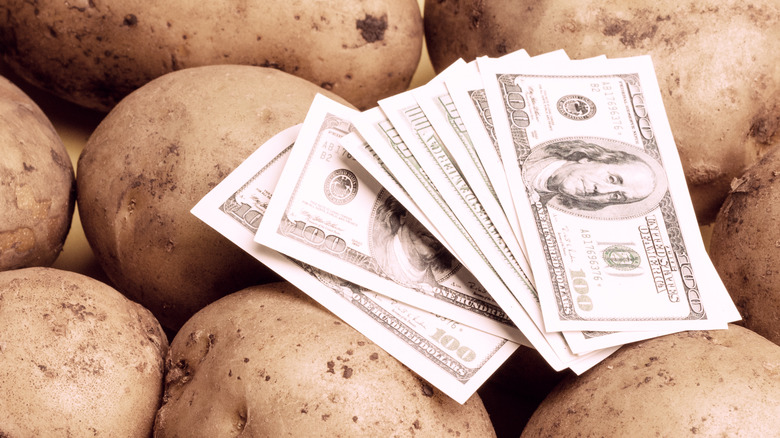 pile of one hundred dollar bills on top of potatoes