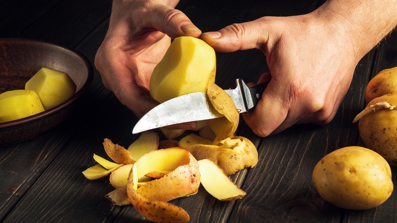 Person peeling potatoes by hand