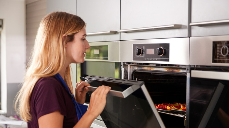 woman checking food in oven