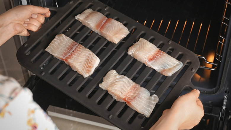 person holding broiler pan with fish
