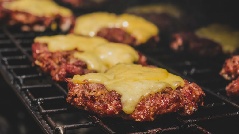 cheeseburgers cooking on grill