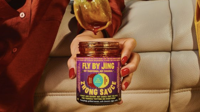 dumpling being dunked into jar of Fly By Jing Zhong Sauce