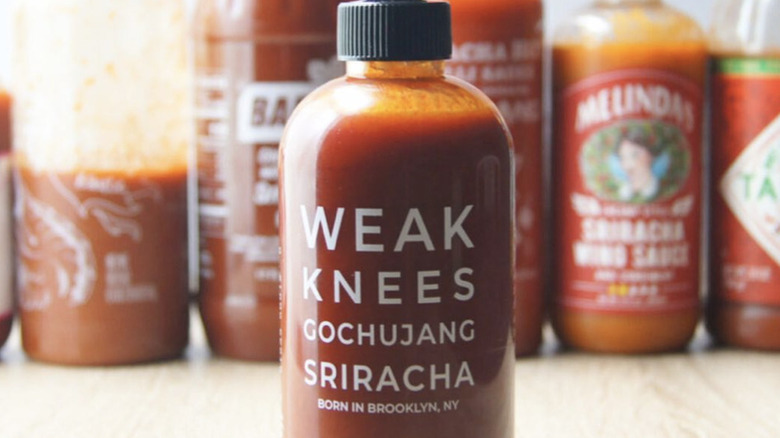 weak Knees Gochujang Sriracha Hot Sauce in front of line up of sriracha sauces