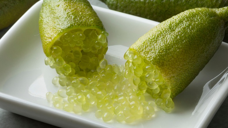 Cut finger limes spilling pearls into dish