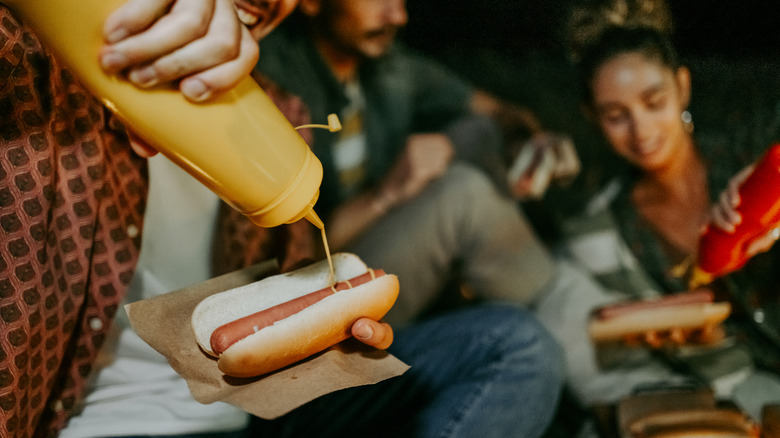 Squirting mustard on hot dog