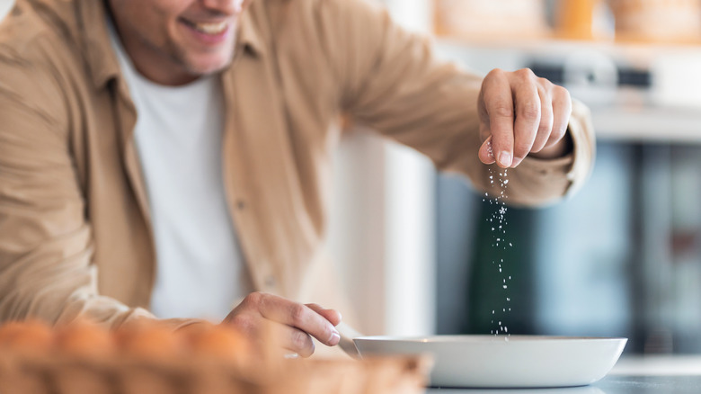 Hand sprinkling salt into large dish