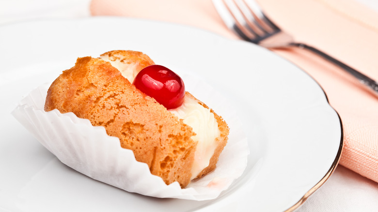 single serving Baba au Rhum topped with whipped cream and cherry