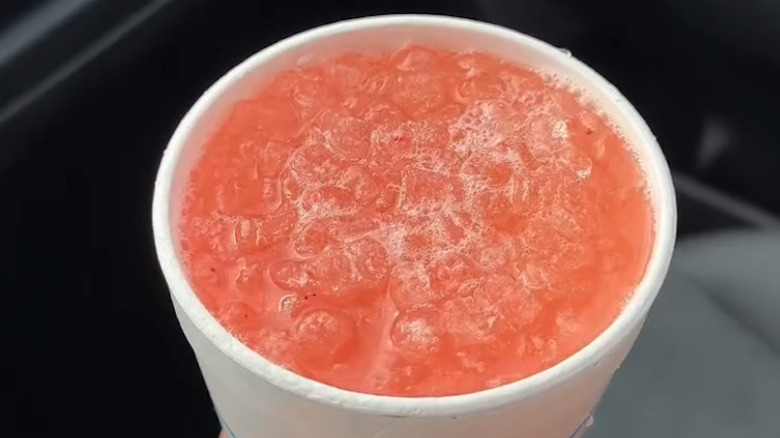 Cup of Sonic's Mermaid Water drink with open lid held above the seat of a car