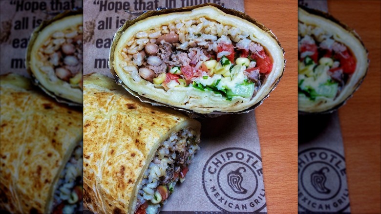 Chipotle Quesarito wrapped in foil and split in half placed on top of a Chipotle paper bag