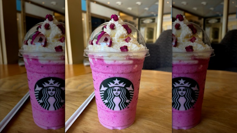 Barbie Frappuccino on wooden table with a straw in a wrapper placed to the left of the drink