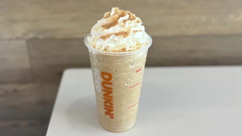 Snickerdoodle Frozen Coffee sitting on a white countertop in front of a wooden wall