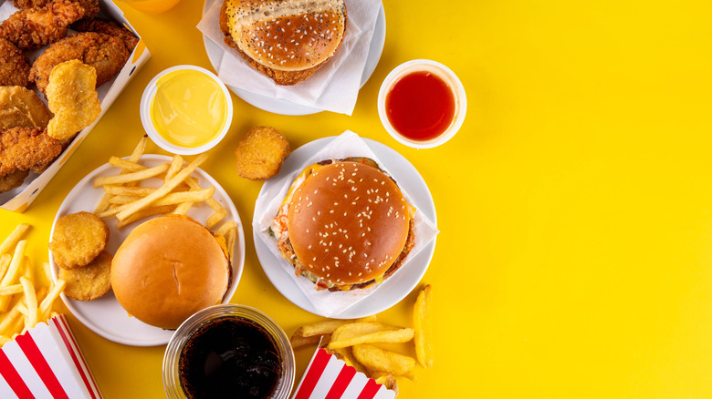 Yellow backdrop with multiple fast food options (burgers, chicken nuggets, fries) placed in the frame