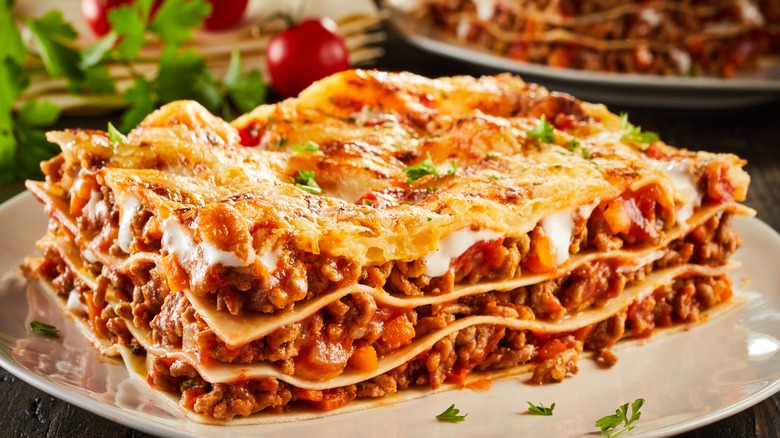 layered meat lasagna with top layer of cheese and crumbs, a sprinkle of herbs