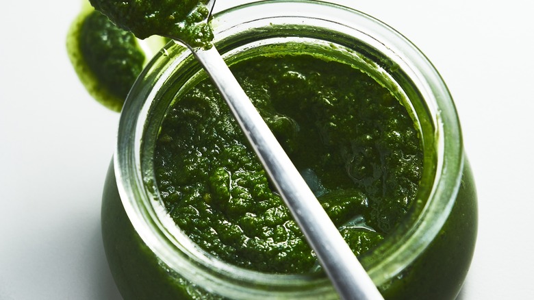 looking into a gleaming green mixture of pesto in jar
