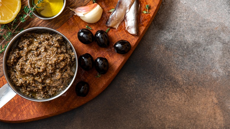 silver bowl of tapenade, 6 olives, garlic, anchovies, partial lemon slice