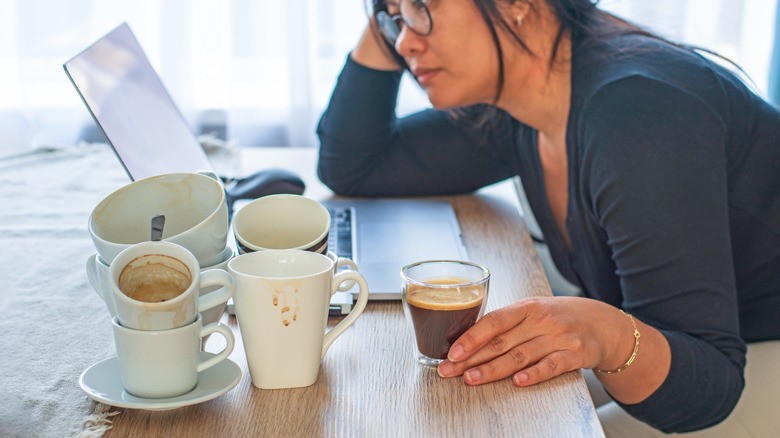 Woman at laptop with many cups of coffee