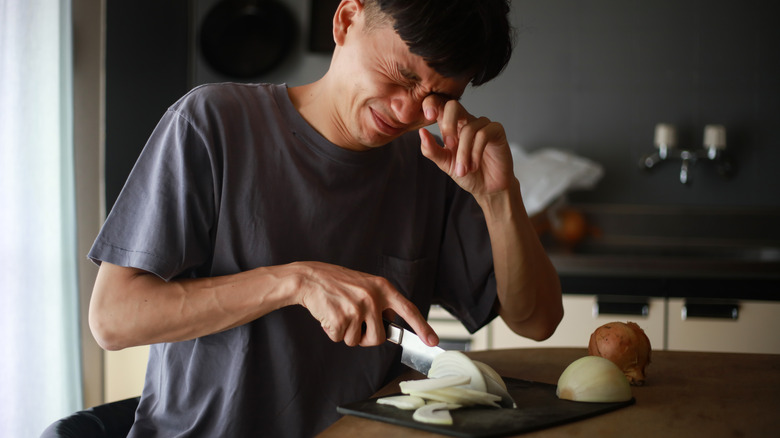 man crying while cutting onions