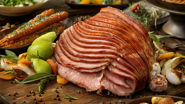 sliced smoked ham on platter surrounded by fruit and veggies