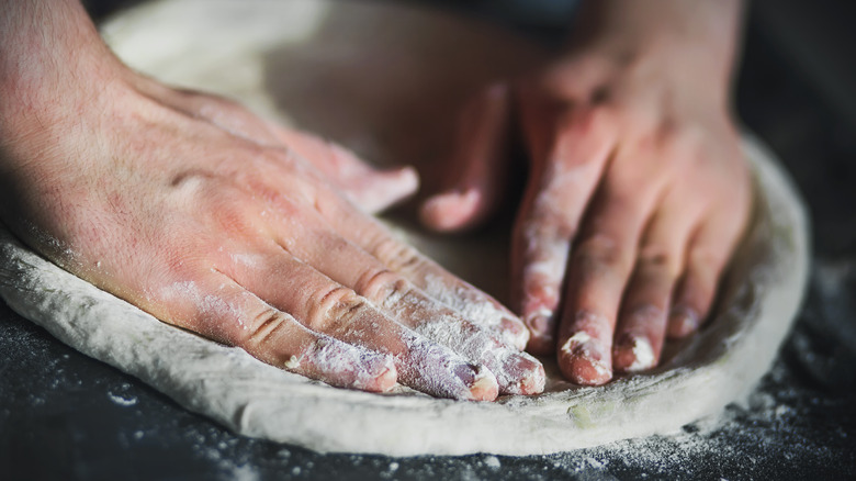 hands pressing dough in pan