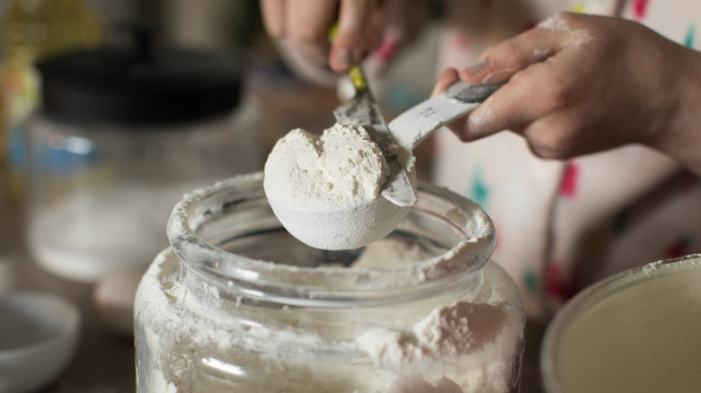 hands leveling a spoon of flour 