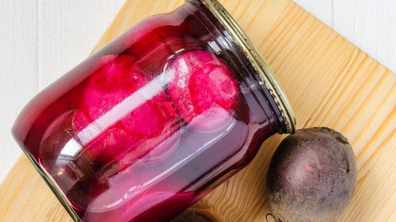 beets in jar with brine and raw beet on board