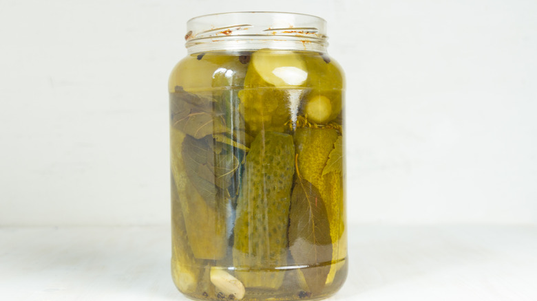 pickles in a jar with pickle juice against white background