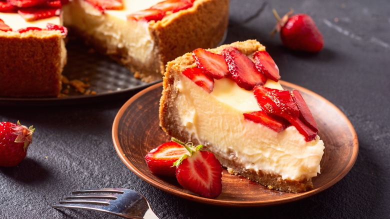 Slice of cheesecake topped with fresh strawberries