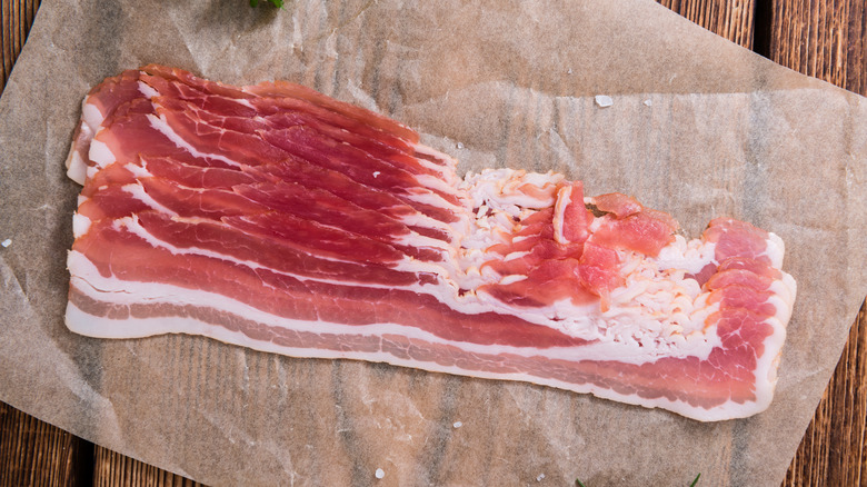 Raw bacon sitting on parchment paper