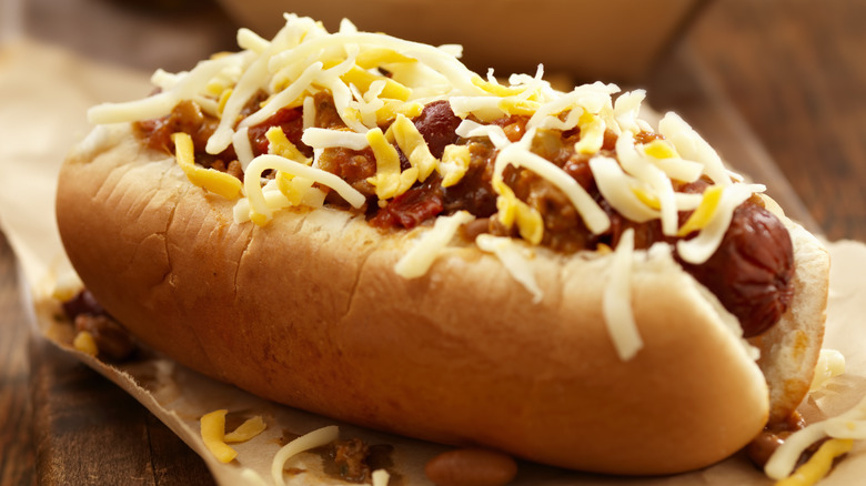 a hot dog topped with chili and shredded cheese