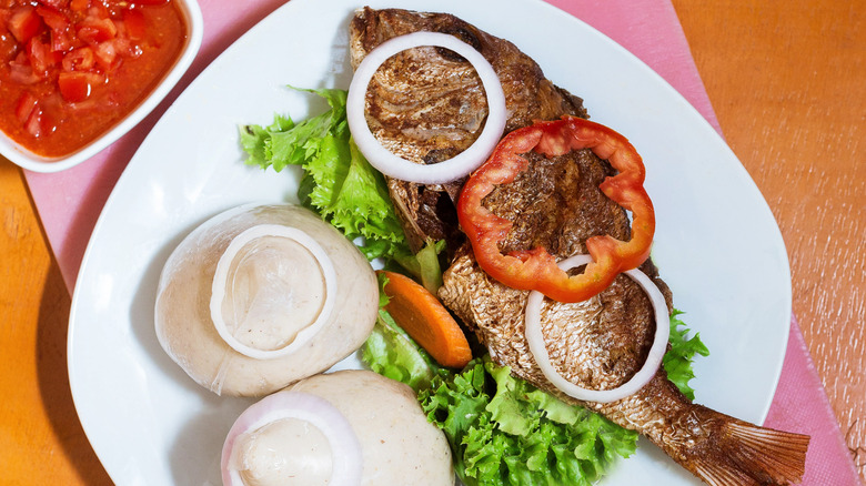 Grilled tilapia with banku and sliced vegetables