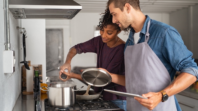 a couple salting a pot of water