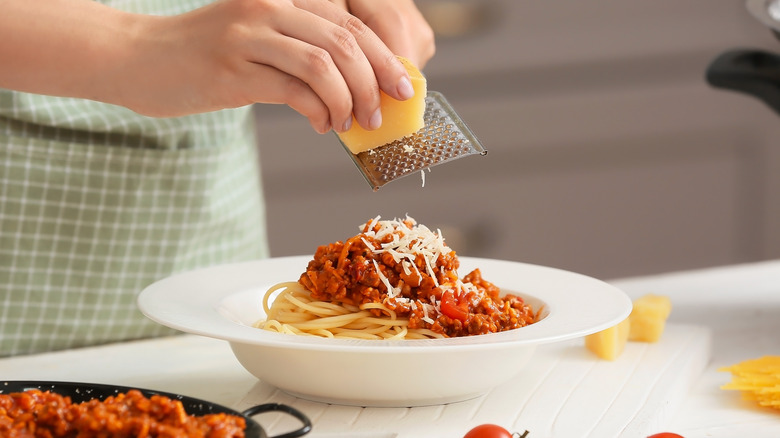 grating cheese on pasta dish