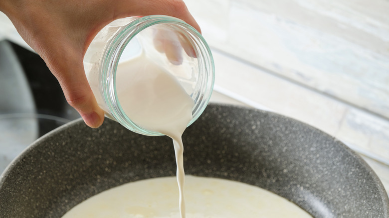 Hand pouring cream into pan