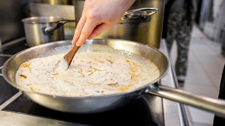 Hand stirring creamy sauce