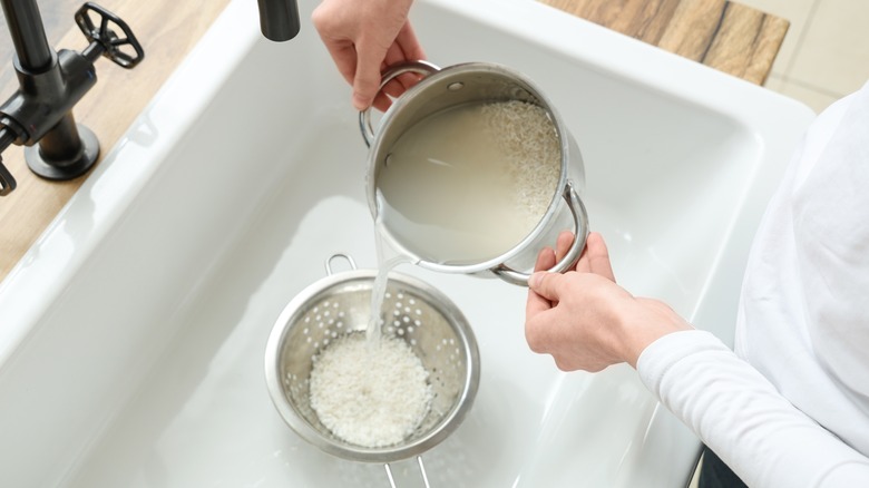 Hands rinsing rice in sink