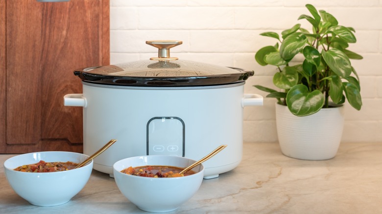 Crock pot with bowls of soup