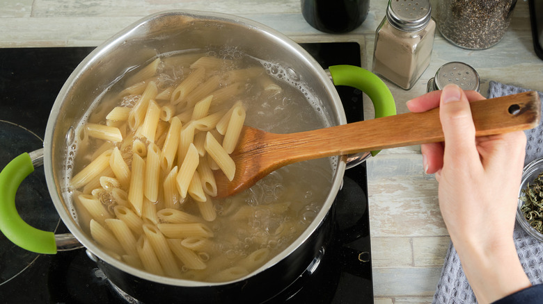 Hand stirring noodles on stove