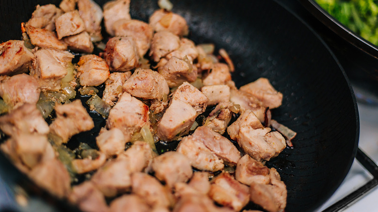 Searing diced chicken in pan