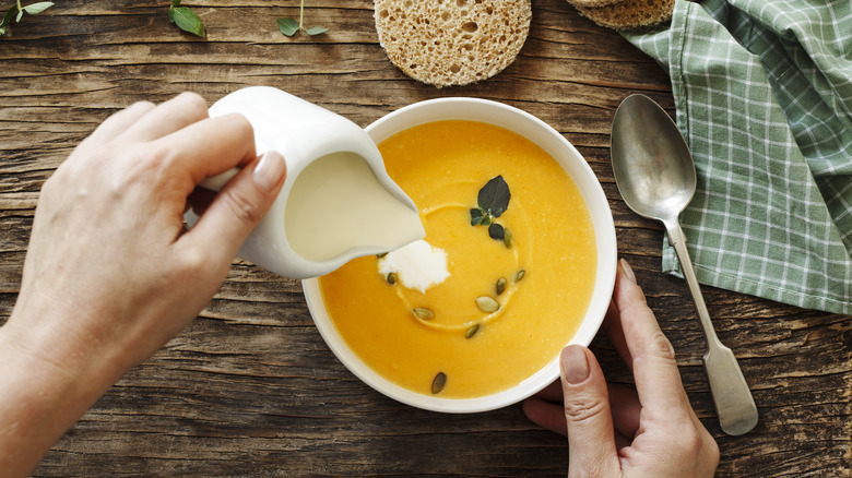 Pouring cream into pumpkin soup