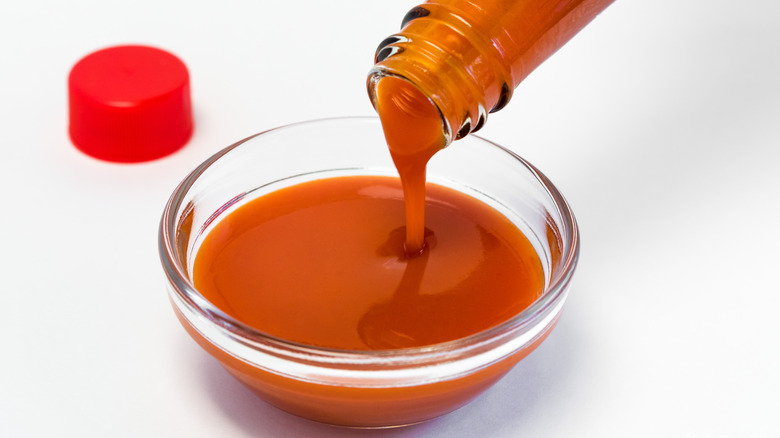 Pouring hot sauce in bowl