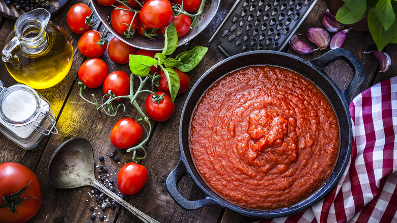 pot of cooked tomato sauce surrounded by its ingredients