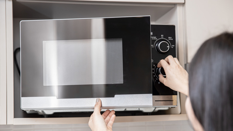 Woman adjusting microwave controls