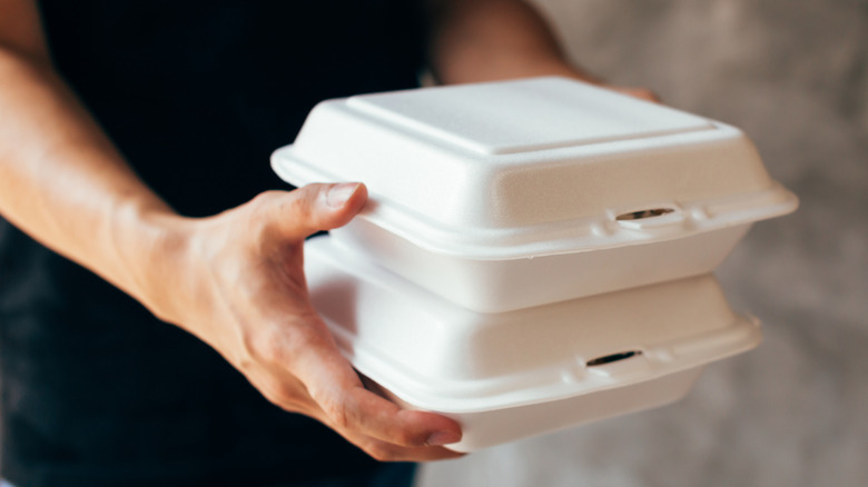 Hands holding Styrofoam takeout containers